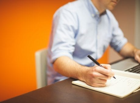 man taking notes in notebook