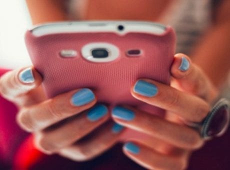 hands with blue fingernails holding pink phone