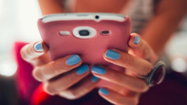 hands with blue fingernails holding pink phone