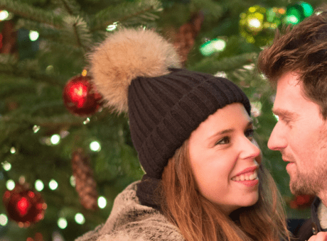 couple looking at each other with a christmas tree