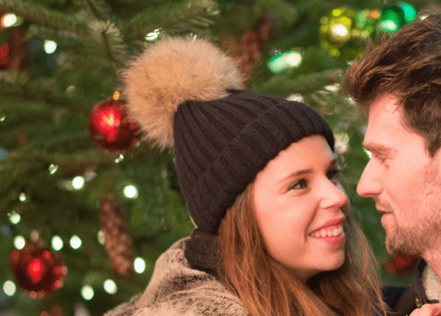 couple looking at each other with a christmas tree